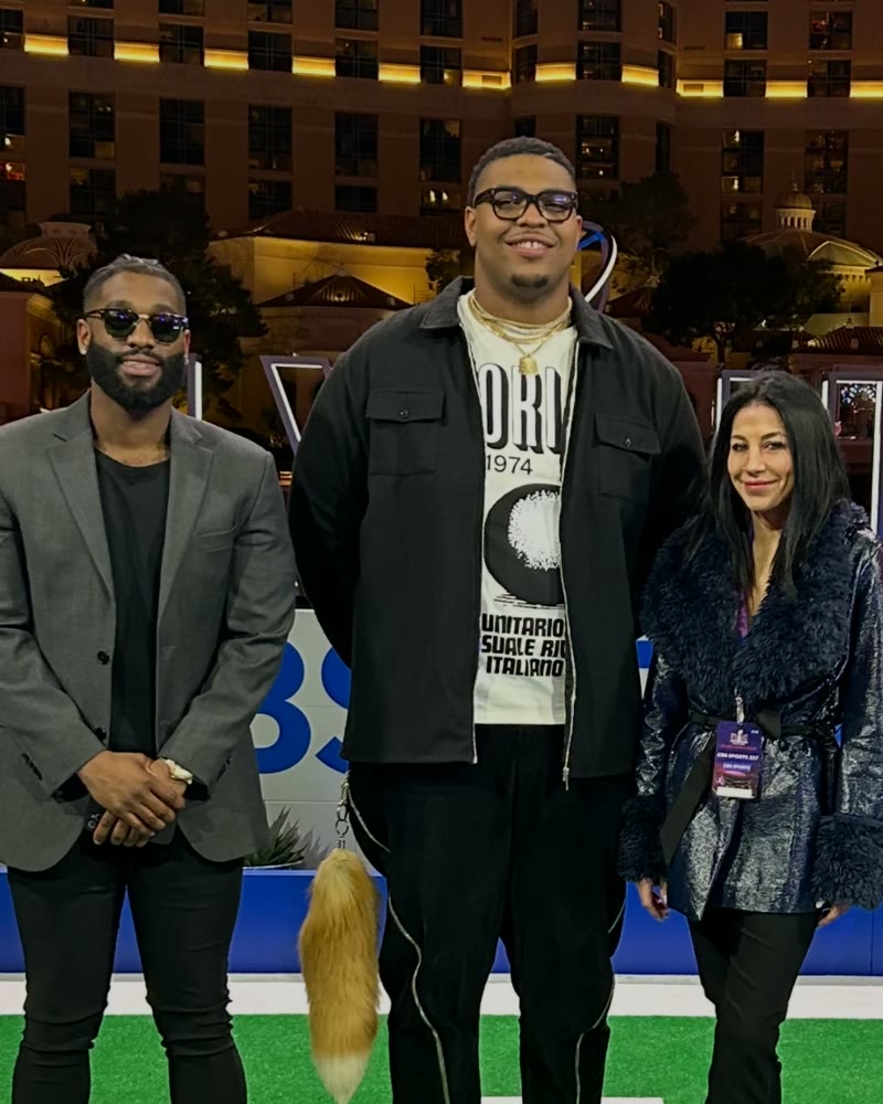 Two men and a woman posing on the CBS Sports set in Las Vegas at night
