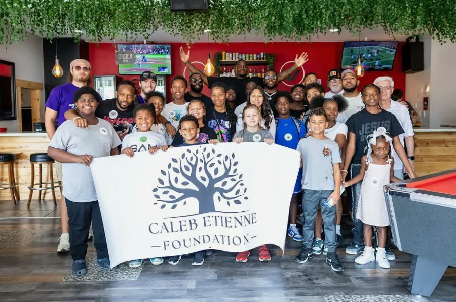 Kids holding a Caleb Etienne Foundation banner at a back-to-school drive