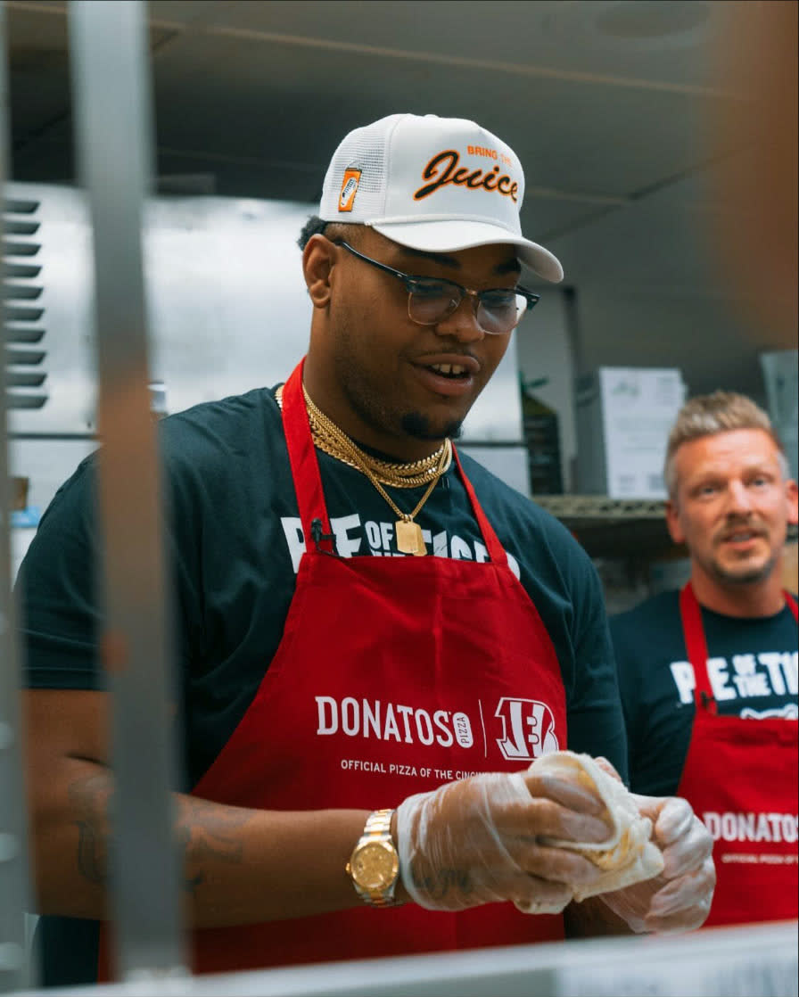 Orlando Brown Jr. making pizza in a Donatos apron