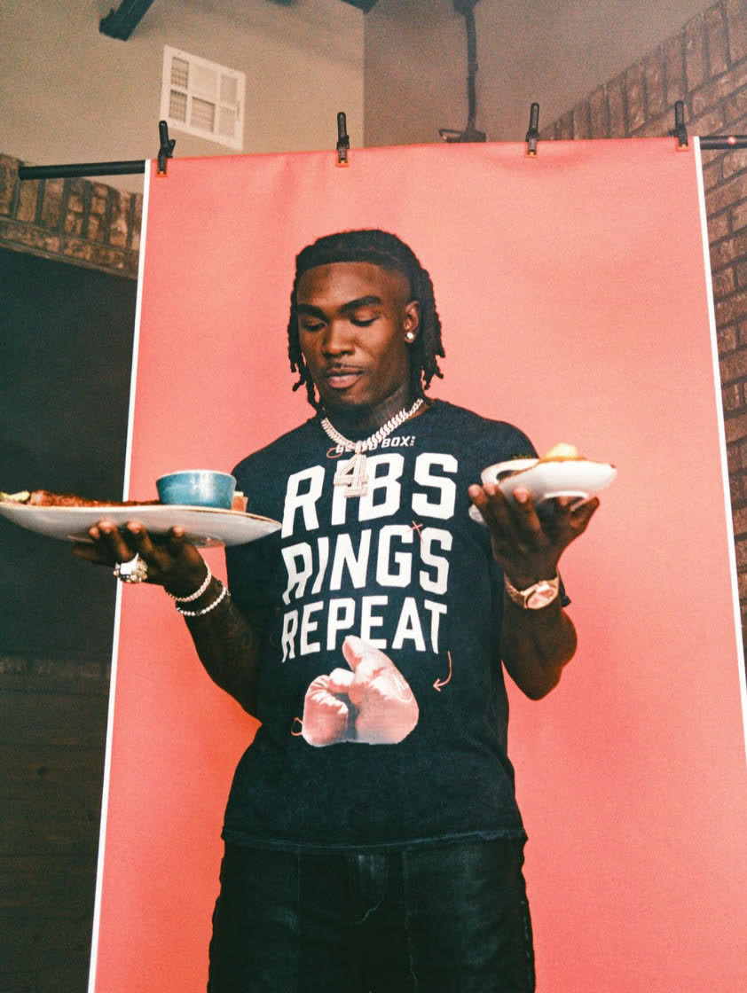 Rashee Rice holding plates of barbecue at a Blind Box BBQ photo shoot